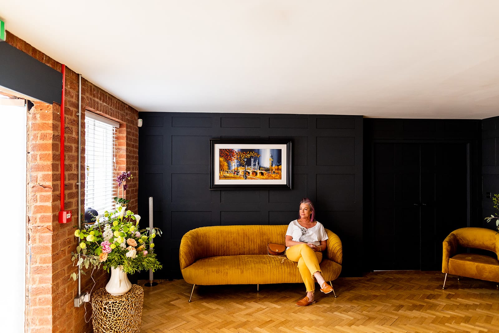 The Hampton Clinic interior — a relaxed seating area with original brick, dark panelling and a velvet sofa